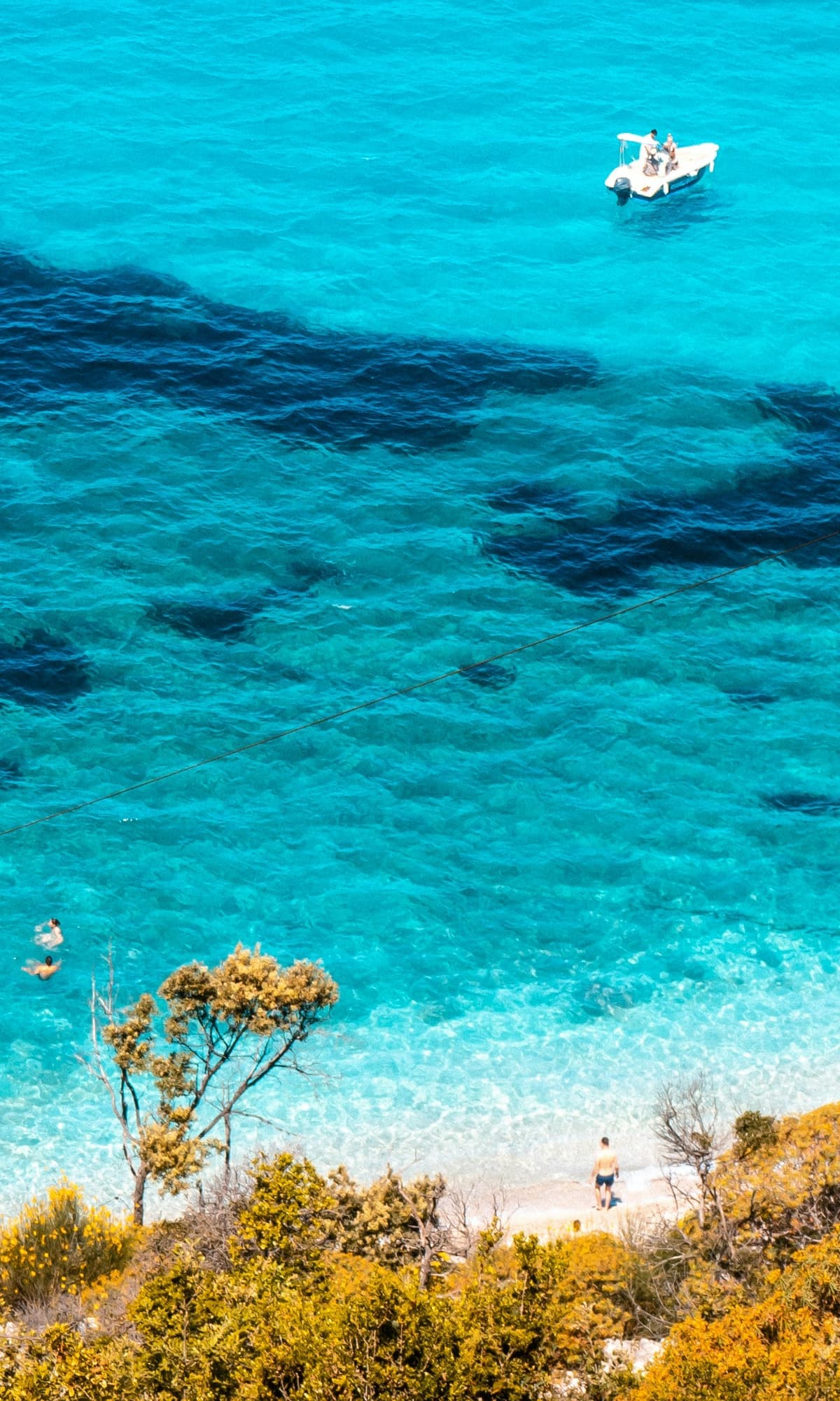 Clear water of Pulëbardha bay near Ksamil, framed by wooded slopes