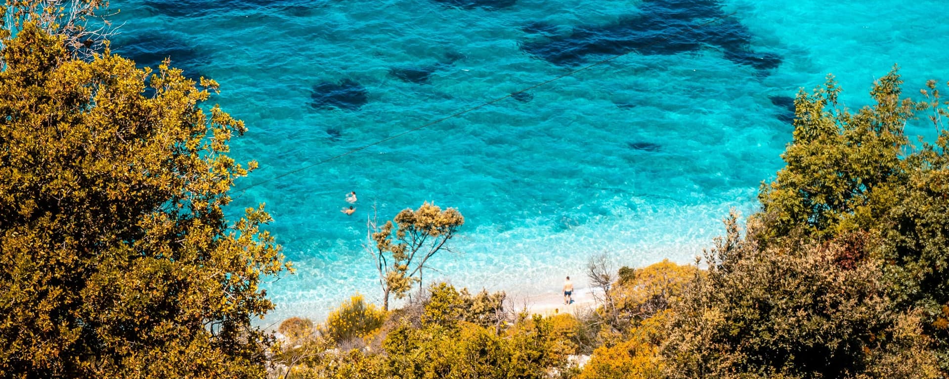Clear water of Pulëbardha bay near Ksamil, framed by wooded slopes